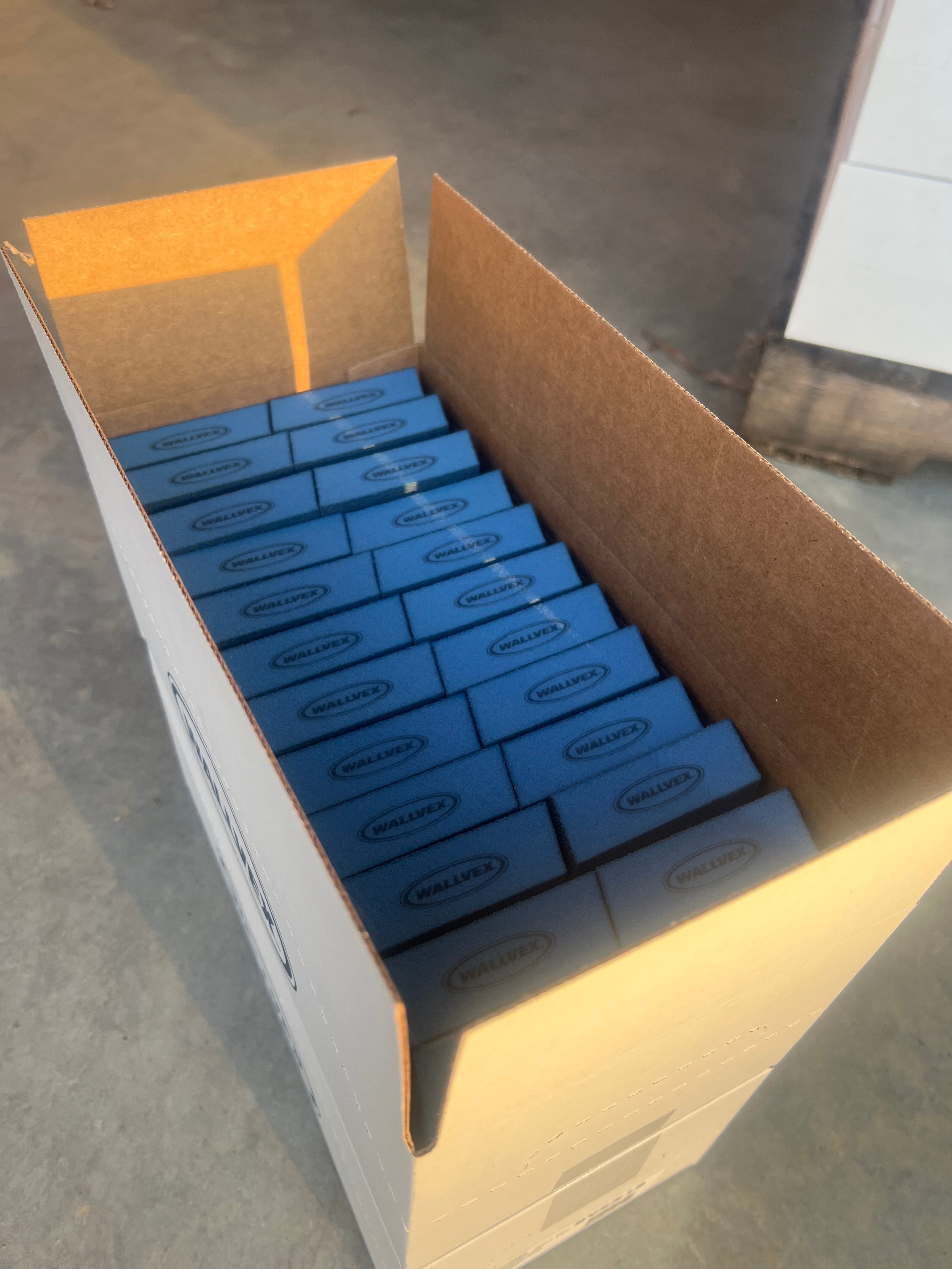 Box of blue Wallvex sanding sponges on a concrete surface